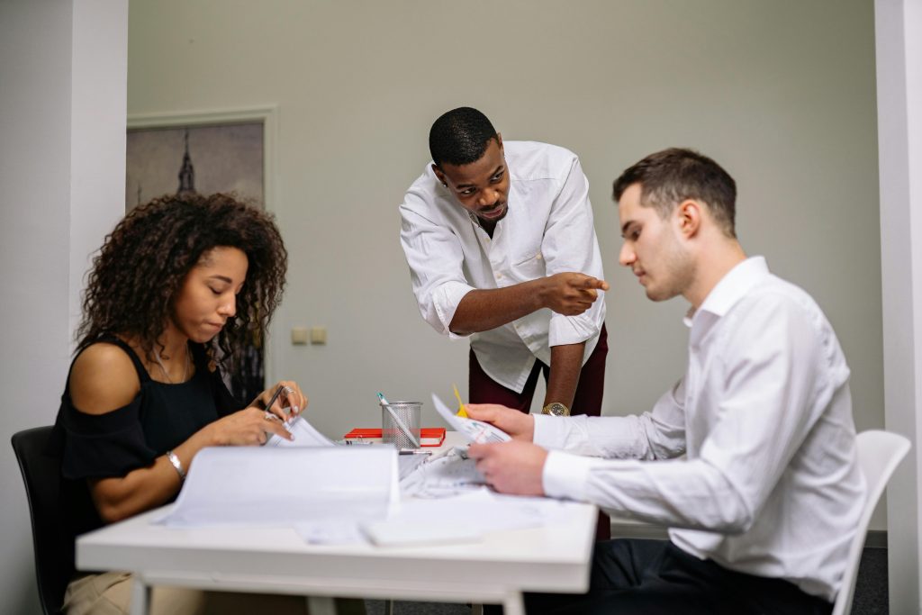 Manager instructing employees during a focused team meeting in a modern office setting.